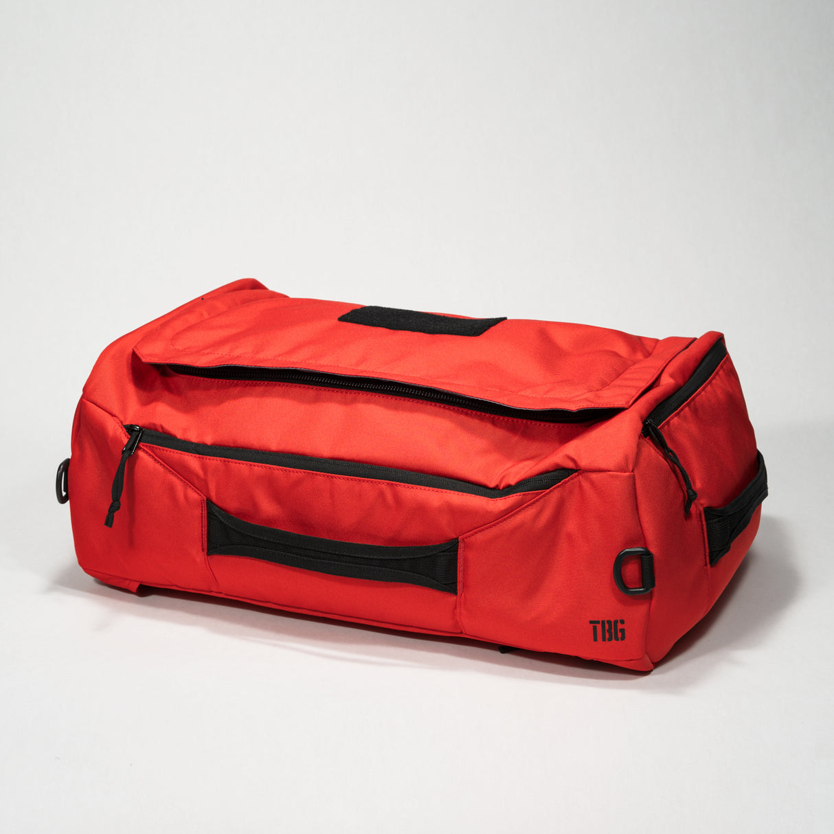 Red duffle bag with black zippers, handles, and D-ring, featuring multiple compartments and a compact, durable design.