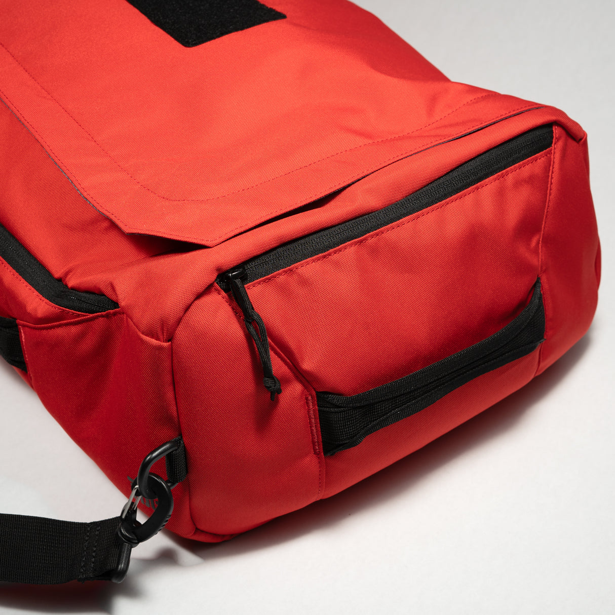 Red duffle bag with black zipper pockets, durable fabric, and adjustable strap for travel or gym use.