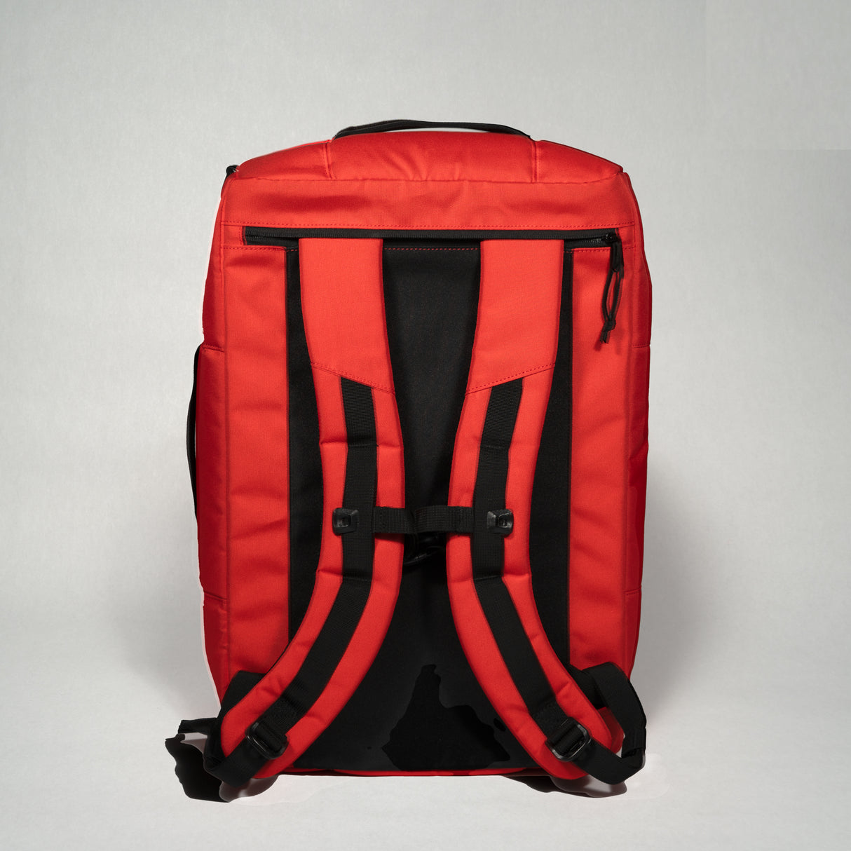 Red and black duffle bag with adjustable shoulder straps, multiple zippered compartments, and durable fabric.