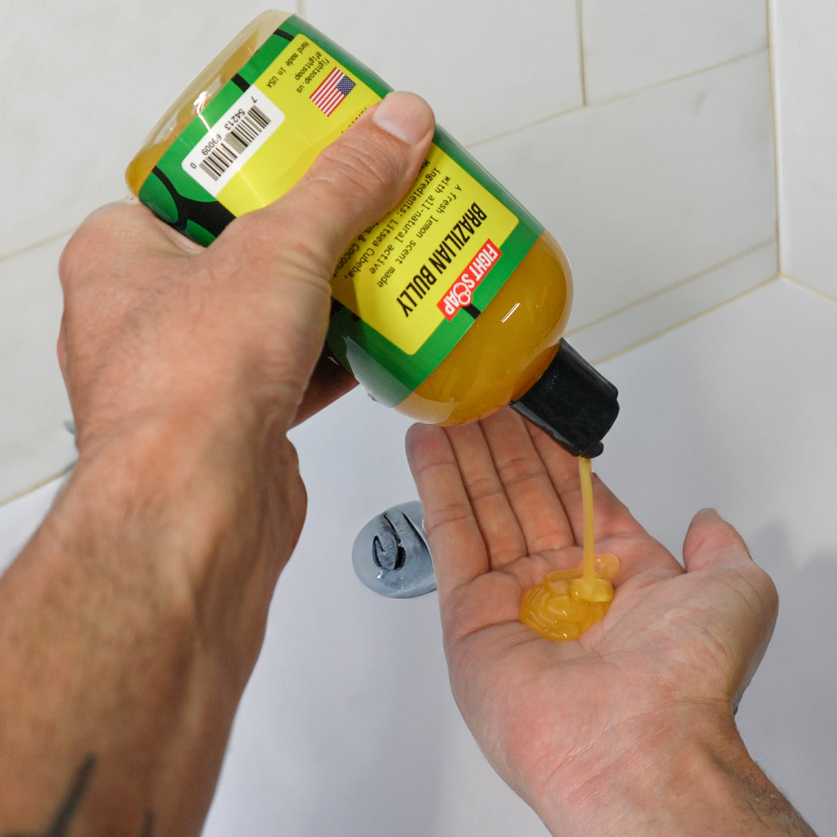 Brazilian Bully Body Wash being poured into a person's hand in a bathroom with white tiled walls.