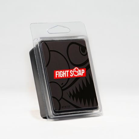 A black soap bar with a cartoonish skull design and "FIGHT SOAP" logo in red and white, inside a clear plastic display case.