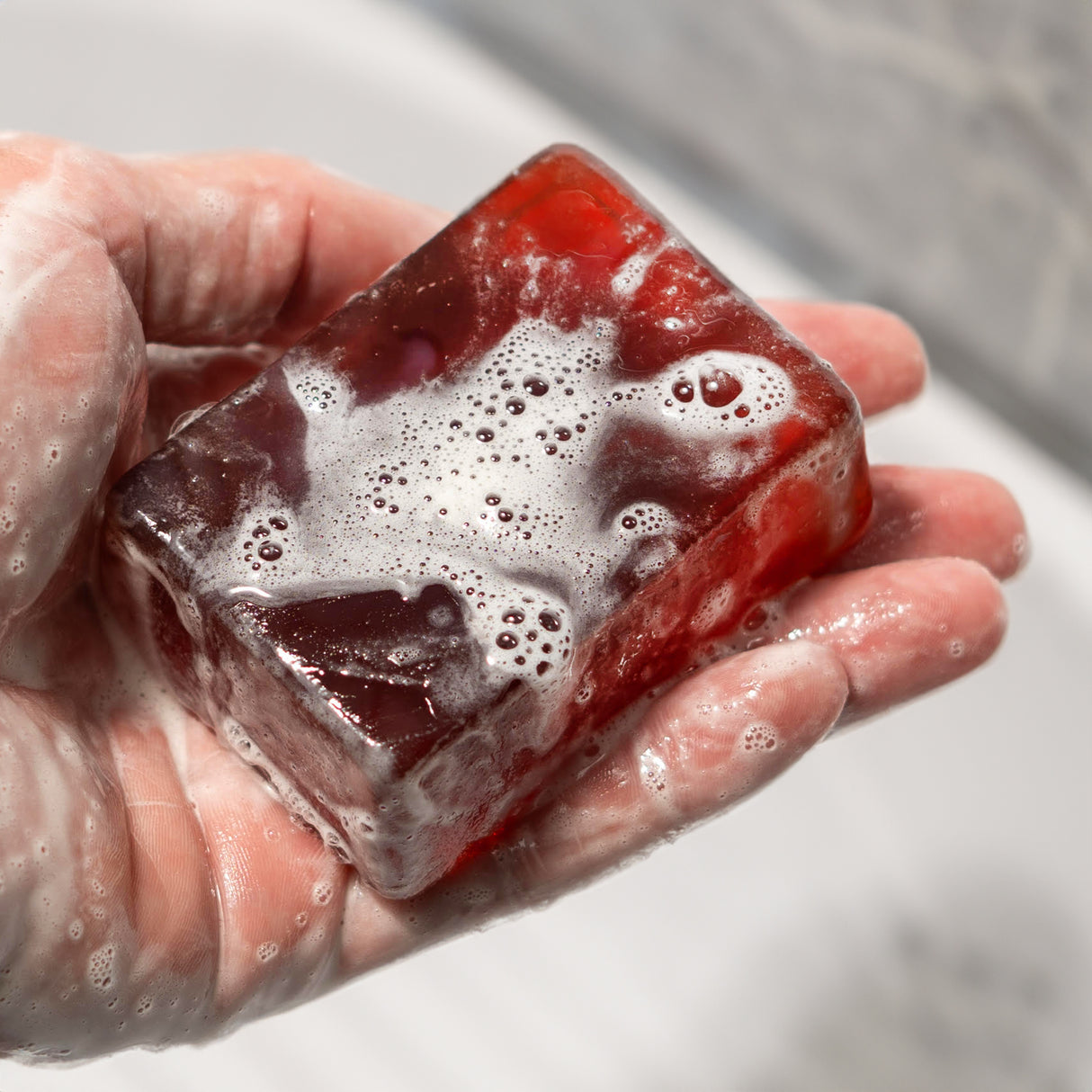 A hand holding a red soap bar with foamy lather, labeled "BLOODY MURDER," resembling blood and soap suds.