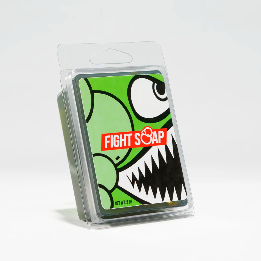 Cartoon-style soap packaging featuring a green dinosaur with sharp teeth, labeled "Fight Soap" in red and white.