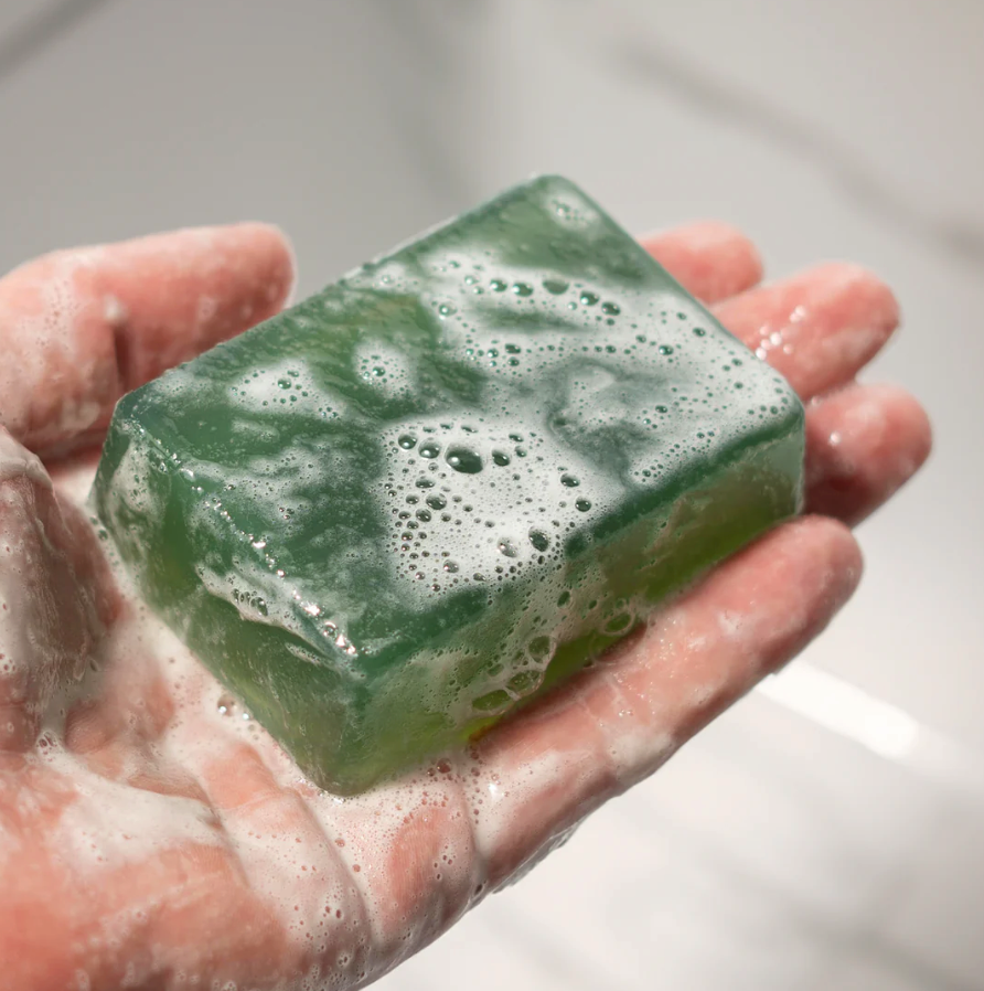 A hand holding a green soap bar with bubbles and lather, appearing wet and freshly used, labeled as DEMO PRODUCT.