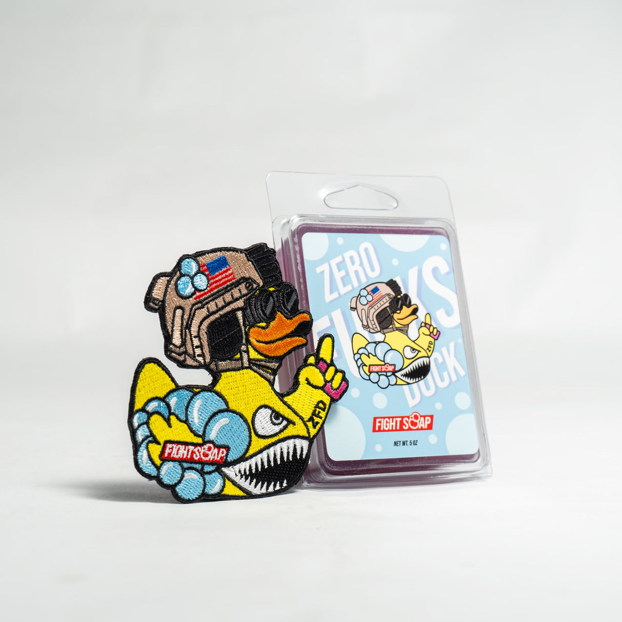 Colorful embroidered patch of a duck wearing a military helmet and sunglasses, with a fierce expression, next to a matching card.