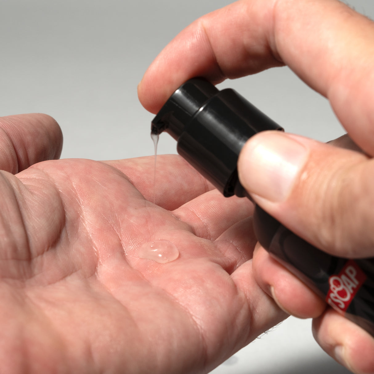 A person dispensing a clear liquid from a black bottle labeled "WAR BEARD" onto their hand, likely a beard care product.
